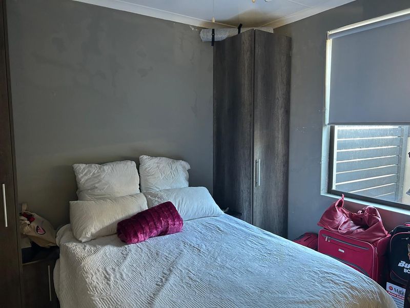 A bedroom featuring a built-in wardrobe and a roller blind. The walls show signs of wear and require cosmetic attention.