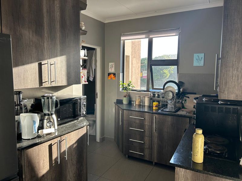 A functional kitchen featuring dark wood-look cabinetry, granite countertops, tiled flooring, and a window providing natural light.