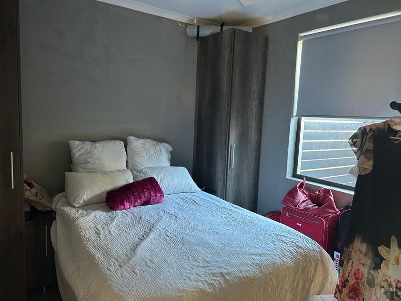 A bedroom featuring built-in cabinetry and a roller blind. The walls and ceiling show signs of wear and require maintenance.