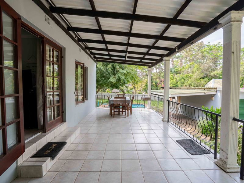 Spacious covered patio featuring tiled flooring, wrought iron railings, and direct access to the home through classic french doors.