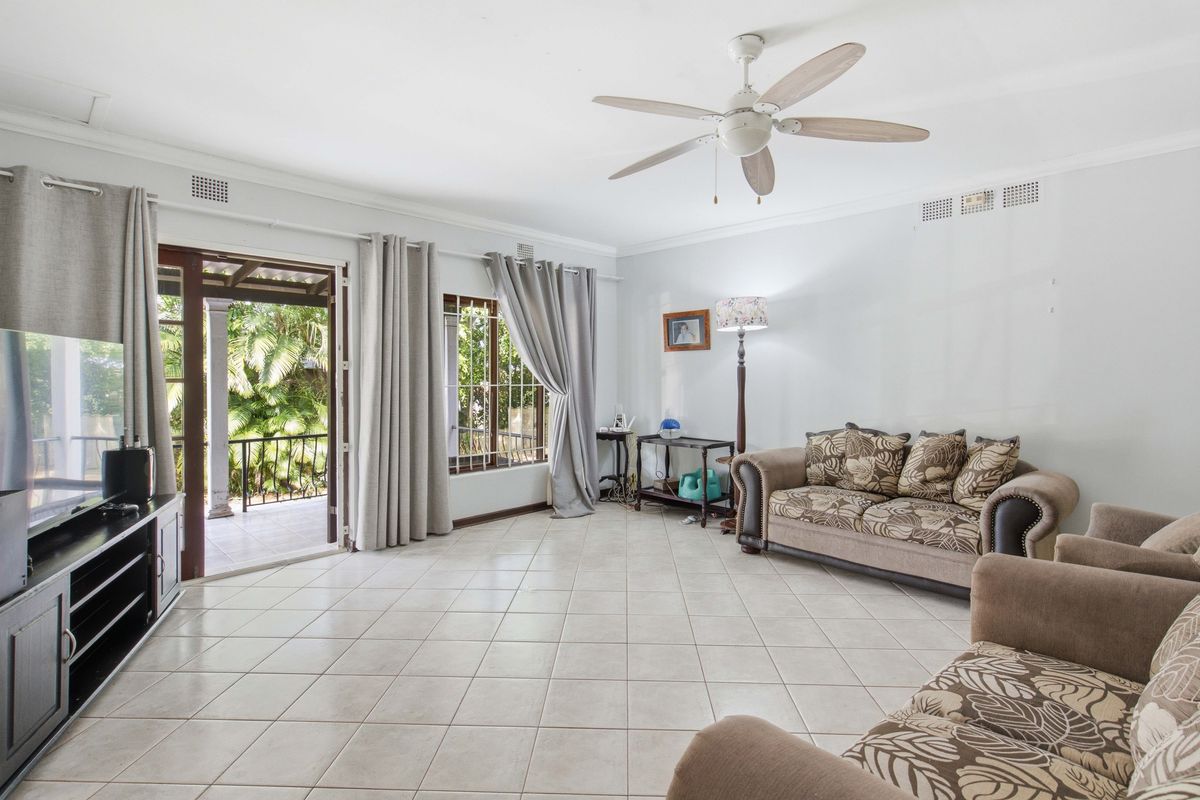 Spacious living room featuring tiled flooring, a ceiling fan, and direct access to an outdoor patio area through sliding glass doors.