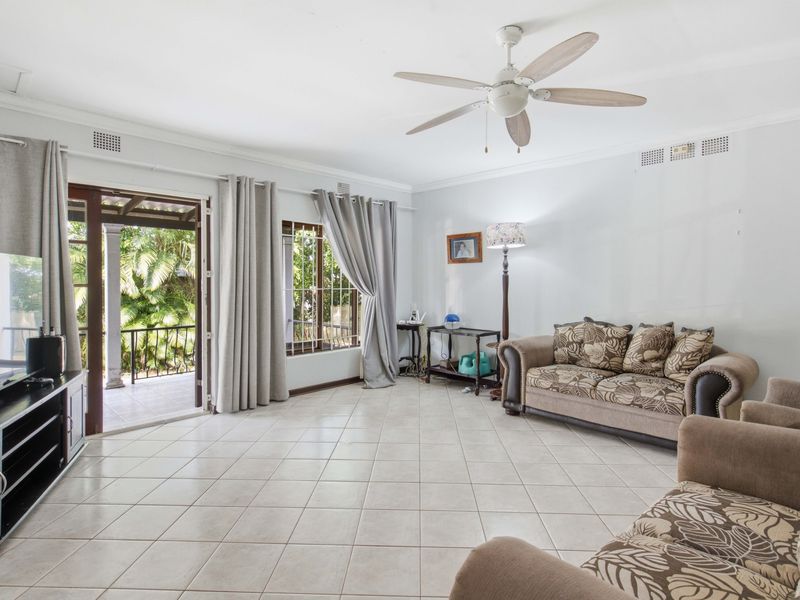 Spacious living room featuring tiled flooring, a ceiling fan, and direct access to an outdoor patio area through sliding glass doors.