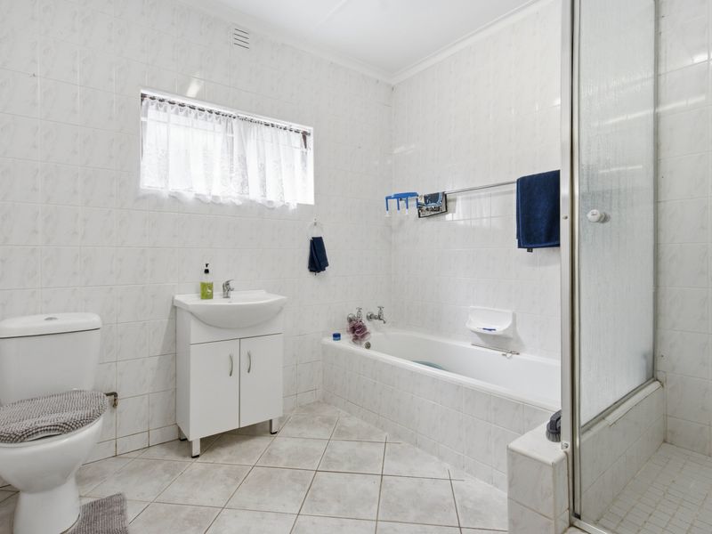 A functional bathroom featuring tiled walls and flooring, a vanity basin, a bathtub, and a separate shower enclosure.