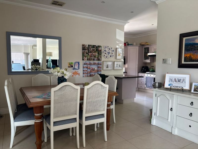 Open plan dining and kitchen area featuring tiled floors, neutral walls, and modern kitchen cabinetry with granite countertops.