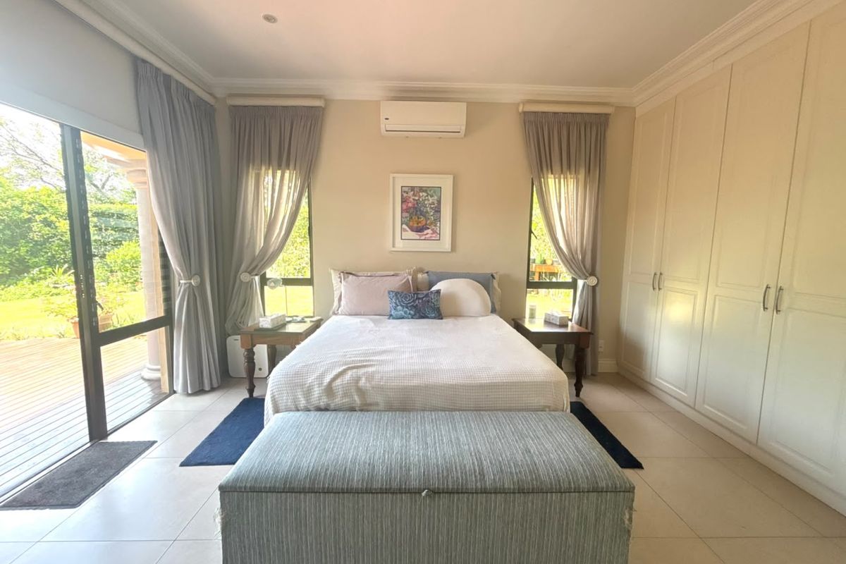 Spacious bedroom featuring built-in wardrobes, tiled flooring, split-system air conditioning, and direct access to an outdoor patio through sliding glass doors.