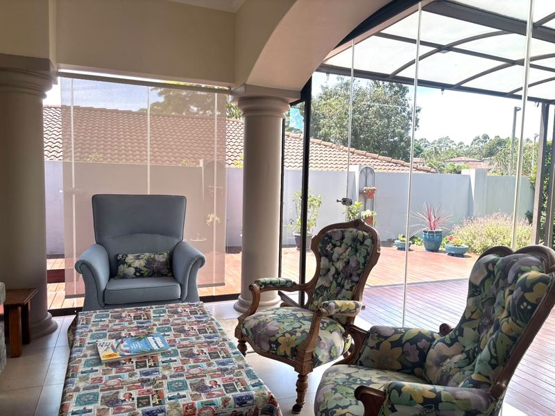Enclosed patio area featuring glass stacker doors, tiled flooring, and structural columns, providing seamless access to the outdoor timber deck.