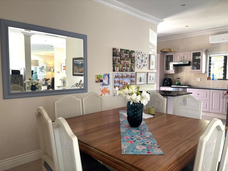 Open-plan dining area flowing into a functional kitchen featuring granite countertops, built-in cabinetry, and a gas hob with an extractor fan.