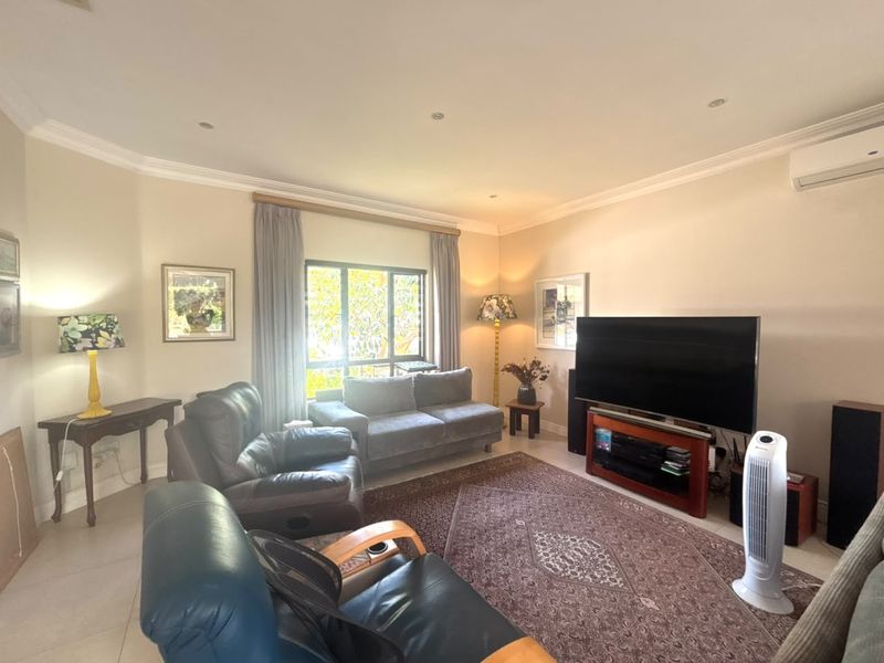 A comfortable living room featuring tiled flooring, crown molding, recessed lighting, and a wall-mounted split-system air conditioner.