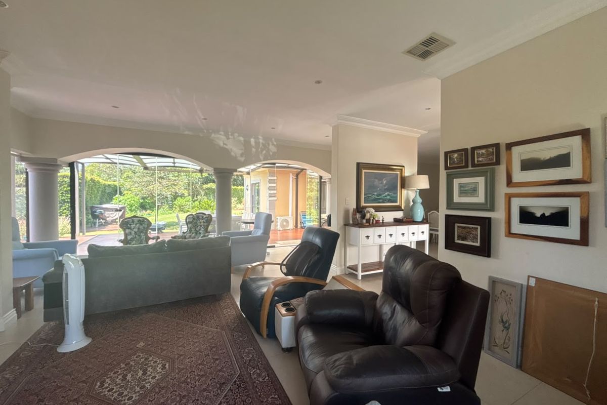 Spacious living room featuring tiled flooring, recessed lighting, and large arched glass doors providing seamless access to the outdoor patio area.