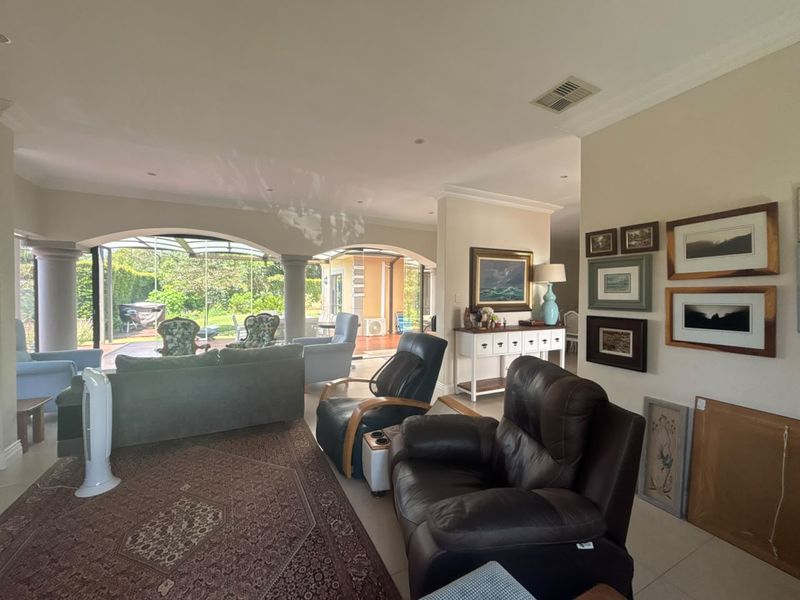 Spacious living room featuring tiled flooring, recessed lighting, and large arched glass doors providing seamless access to the outdoor patio area.