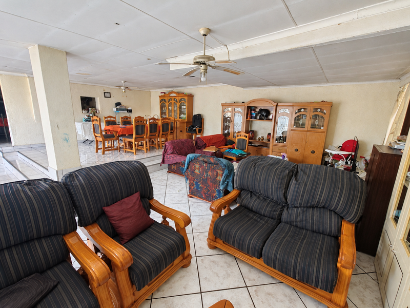 Spacious open-plan living and dining area featuring tiled flooring, ceiling fans, and built-in cabinetry, offering a versatile layout for family living.