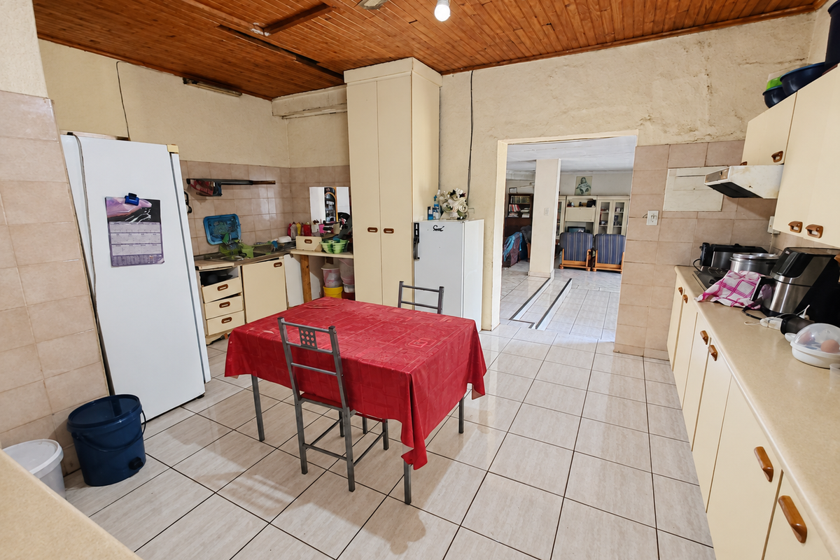 A dated kitchen featuring tiled flooring, timber ceiling, and built-in cabinetry, offering significant potential for modernization and renovation.