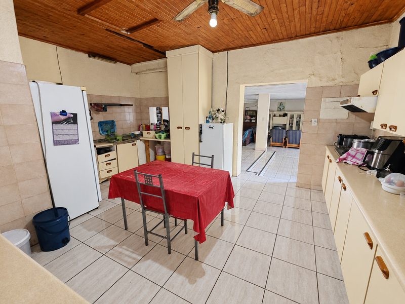 A dated kitchen featuring tiled flooring, timber ceiling, and built-in cabinetry, offering significant potential for modernization and renovation.