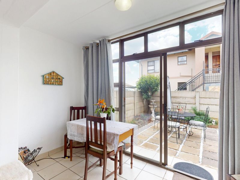Bright living area featuring tiled flooring and a large sliding glass door providing direct access to the outdoor patio and garden space.