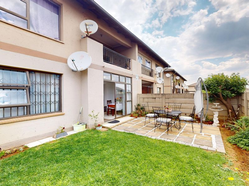 Rear view of the apartment featuring a private garden, paved patio area, and direct access via sliding glass doors.