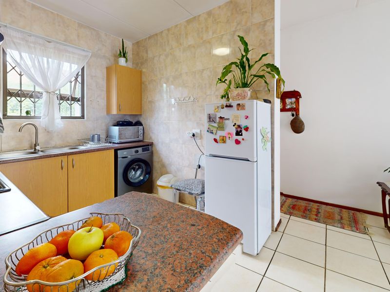 Functional kitchen featuring granite countertops, laminate cabinetry, ceramic wall and floor tiling, and integrated hob with extractor fan.