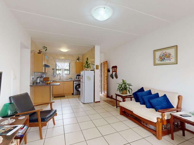 An open-plan living and kitchen area featuring tiled flooring, functional cabinetry, and a combined layout suitable for comfortable apartment living.