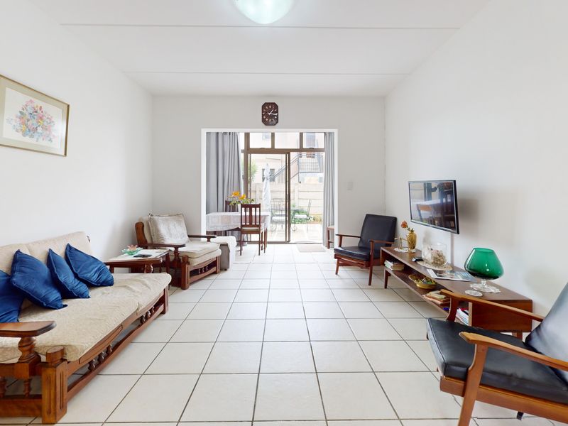 A bright living room featuring tiled flooring and a large sliding glass door that provides access to an outdoor patio area.