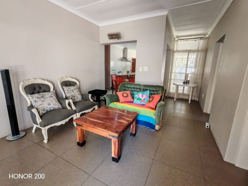 Open plan living area featuring neutral wall tones, tiled flooring, and a view through to the kitchen area with an extractor fan.