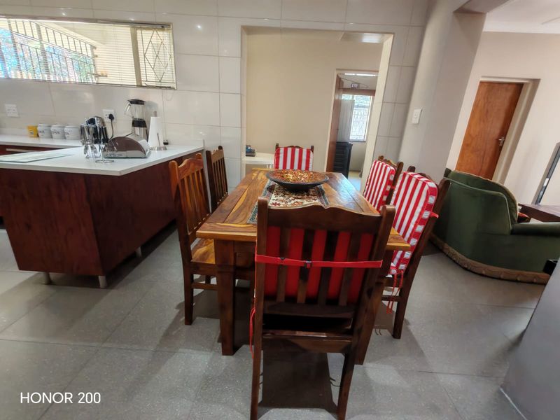 Open plan kitchen and dining area featuring tiled flooring, a kitchen island with built-in cabinetry, and a neutral tiled splashback.