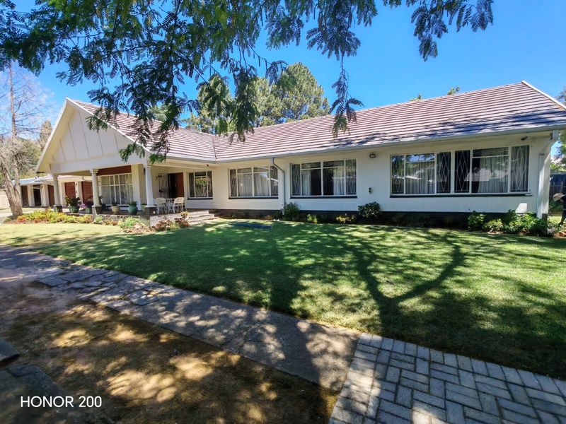 A well-maintained single-story residential property featuring a tiled roof, covered front patio, and a spacious, manicured front lawn.