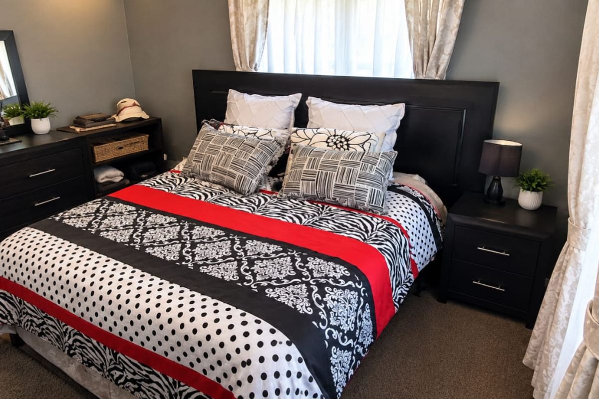 A well-maintained bedroom featuring neutral wall tones, carpeted flooring, and large windows that allow for natural light.