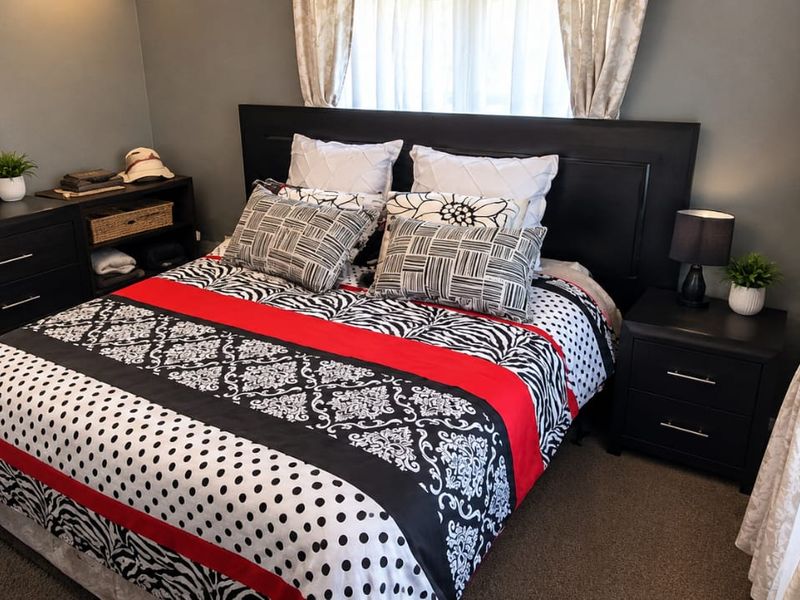 A well-maintained bedroom featuring neutral wall tones, carpeted flooring, and large windows that allow for natural light.