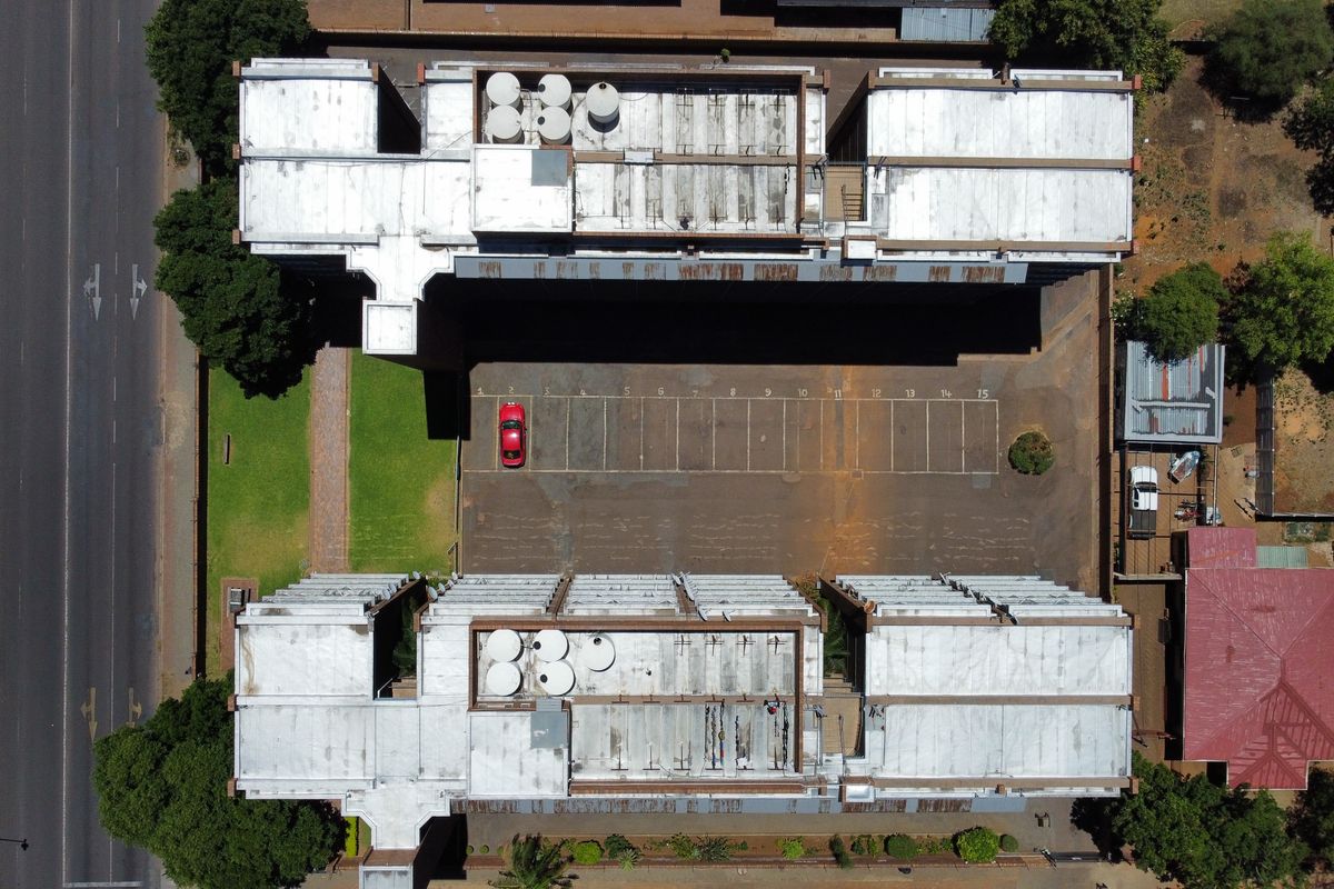 Aerial view of the townhouse complex showing the roof structure, water tanks, and designated parking area.