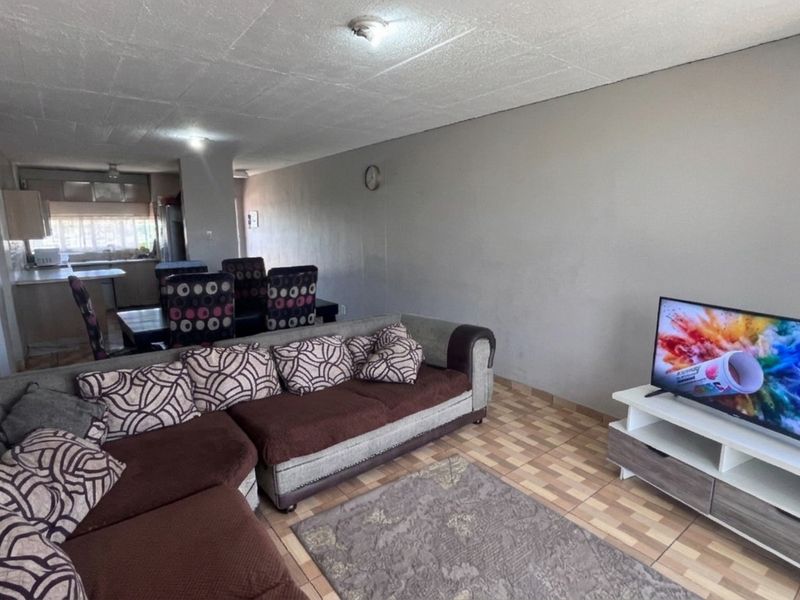 Open-plan living and dining area featuring tiled flooring and a connected kitchen space, offering a functional layout for daily living.