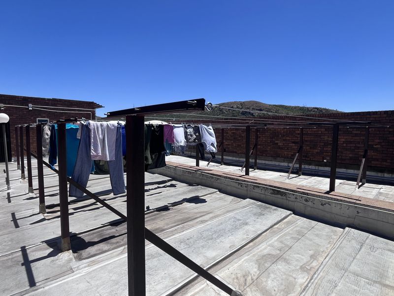 An open-air rooftop patio area featuring brick boundary walls and a fixed metal washing line structure.