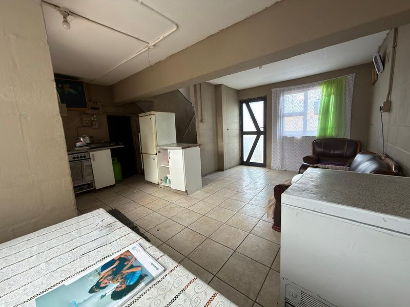 Open-plan living and kitchen area featuring tiled flooring, built-in cabinetry, and direct access to the exterior.
