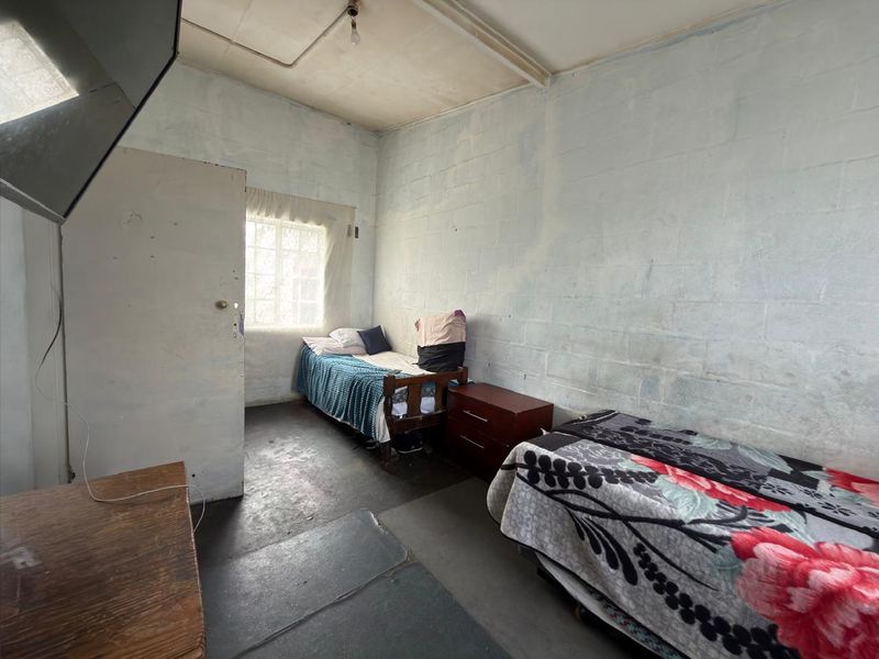 A bedroom featuring exposed concrete block walls and basic finishes, offering a blank canvas for renovation and cosmetic updates.