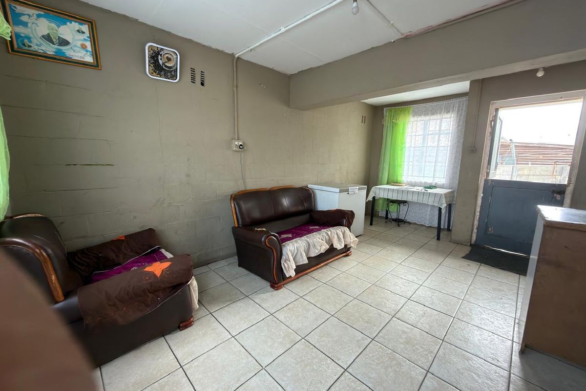 A living area featuring tiled flooring, exposed electrical conduit, and direct access to the exterior through a door.
