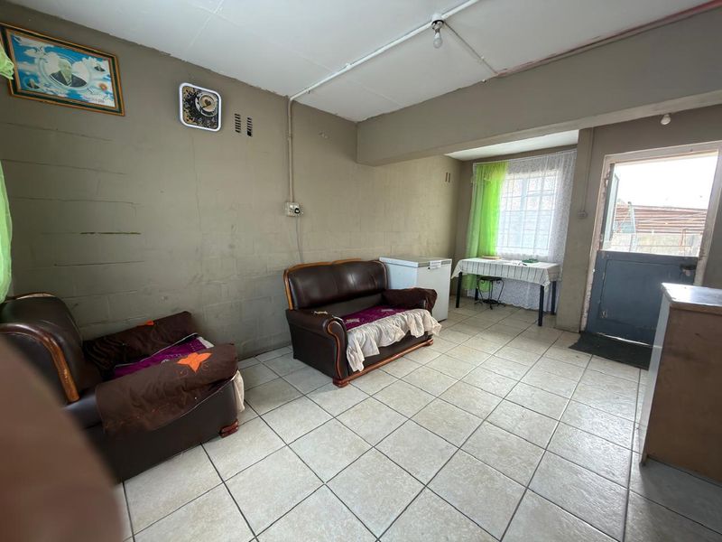 A living area featuring tiled flooring, exposed electrical conduit, and direct access to the exterior through a door.