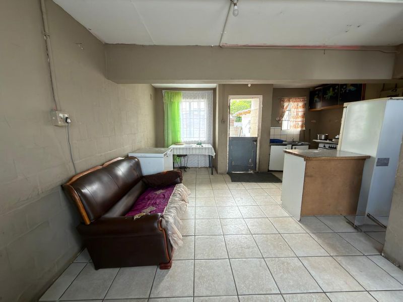 Open plan living and kitchen area featuring tiled flooring, basic cabinetry, and direct access to the exterior.