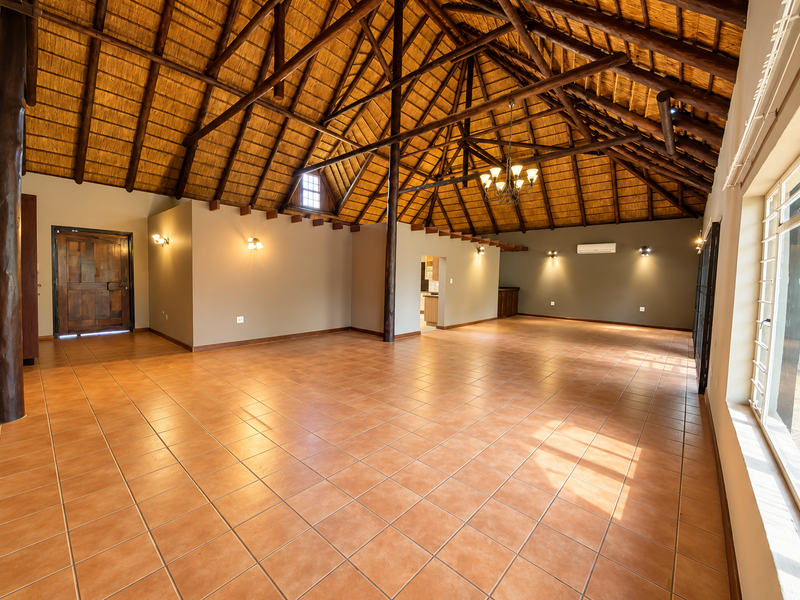 Spacious living area featuring a high vaulted thatched ceiling with exposed timber trusses, ceramic tile flooring, and integrated air conditioning.