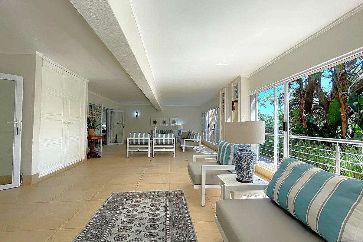 A bright and spacious living area featuring large windows, tiled flooring, and built-in storage, offering a comfortable and airy atmosphere.