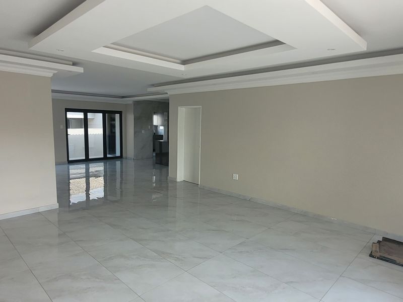 Spacious open-plan living area featuring modern recessed ceilings, neutral wall finishes, and high-gloss porcelain floor tiles with seamless access to outdoor spaces.