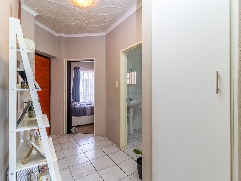 A functional hallway featuring tiled flooring and a textured ceiling, providing access to adjacent rooms including a bedroom and bathroom.