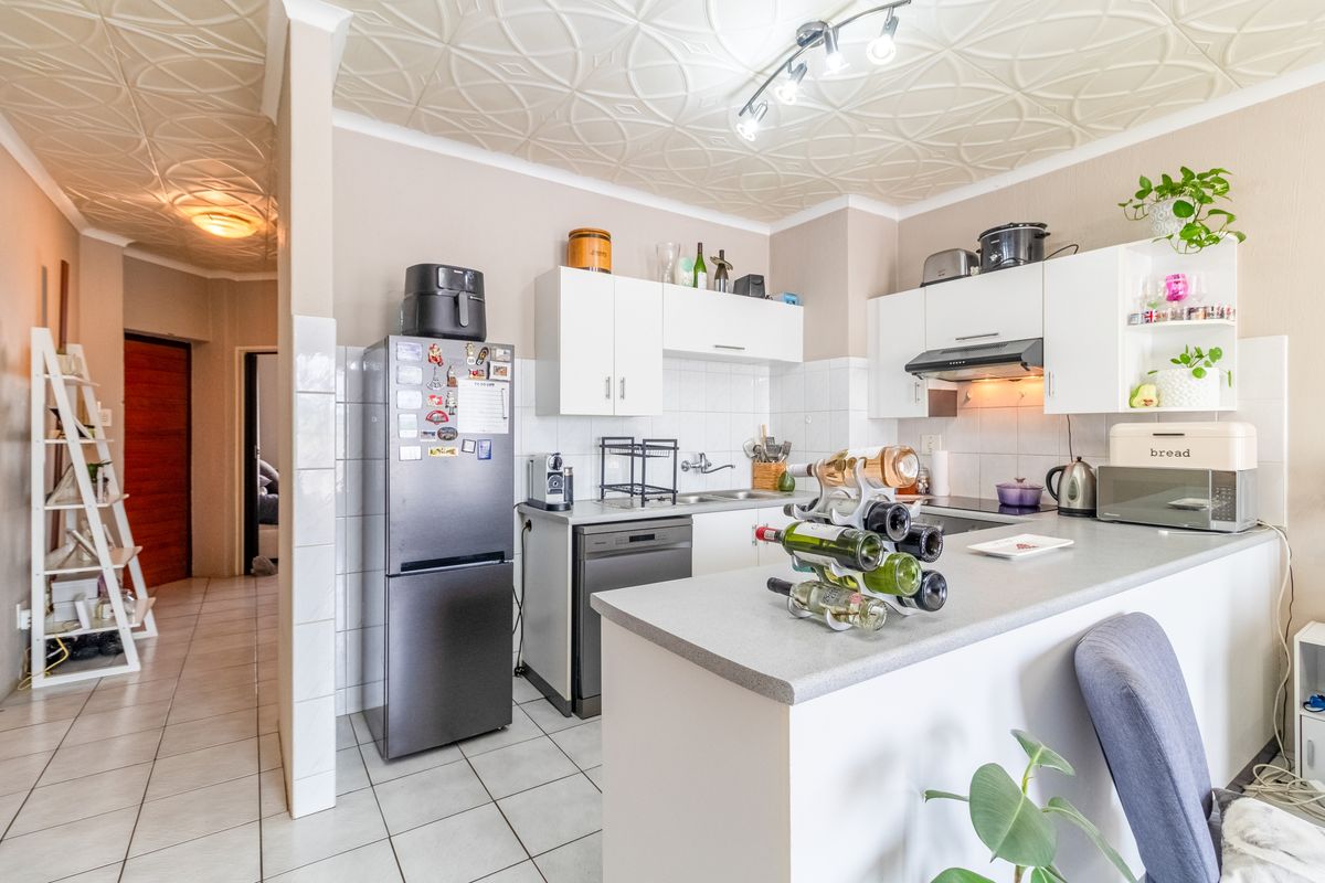 A functional kitchen featuring white cabinetry, laminate countertops, a tiled backsplash, and unique decorative ceiling tiles, providing a practical workspace for daily cooking.
