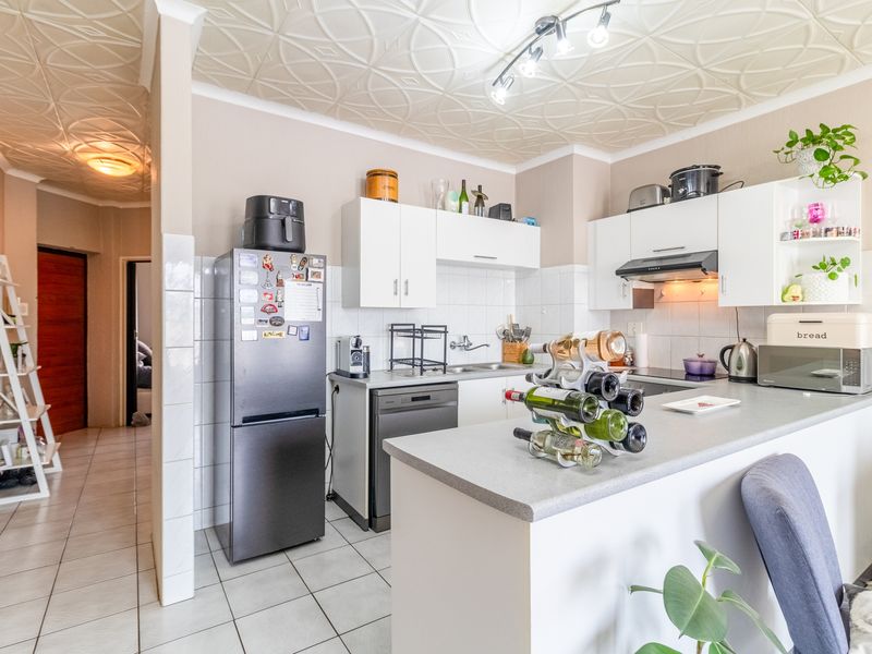 A functional kitchen featuring white cabinetry, laminate countertops, a tiled backsplash, and unique decorative ceiling tiles, providing a practical workspace for daily cooking.