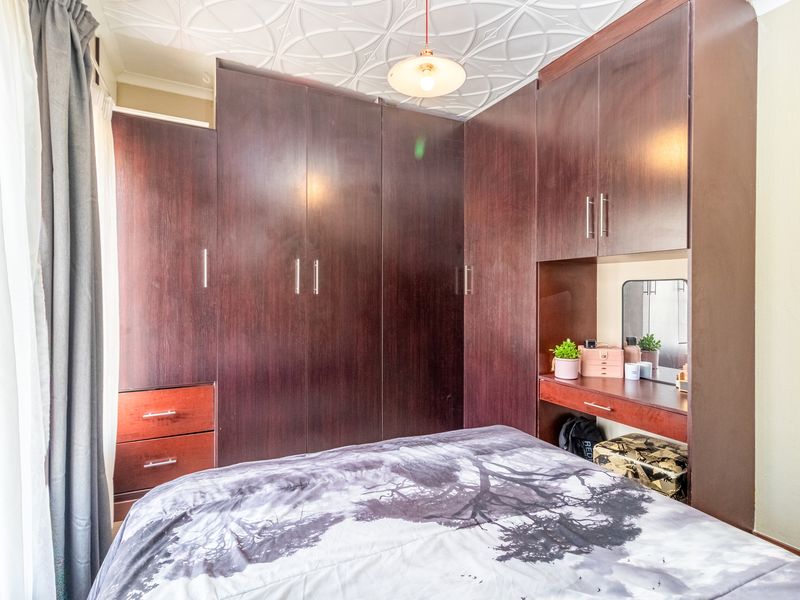 Bedroom featuring extensive dark wood built-in cupboards with an integrated vanity station and unique decorative ceiling detailing.