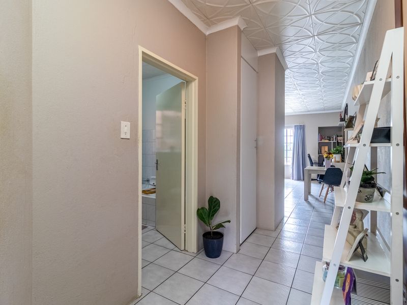 A functional hallway featuring tiled flooring and decorative ceiling tiles, providing access to adjacent rooms including a bathroom and living area.