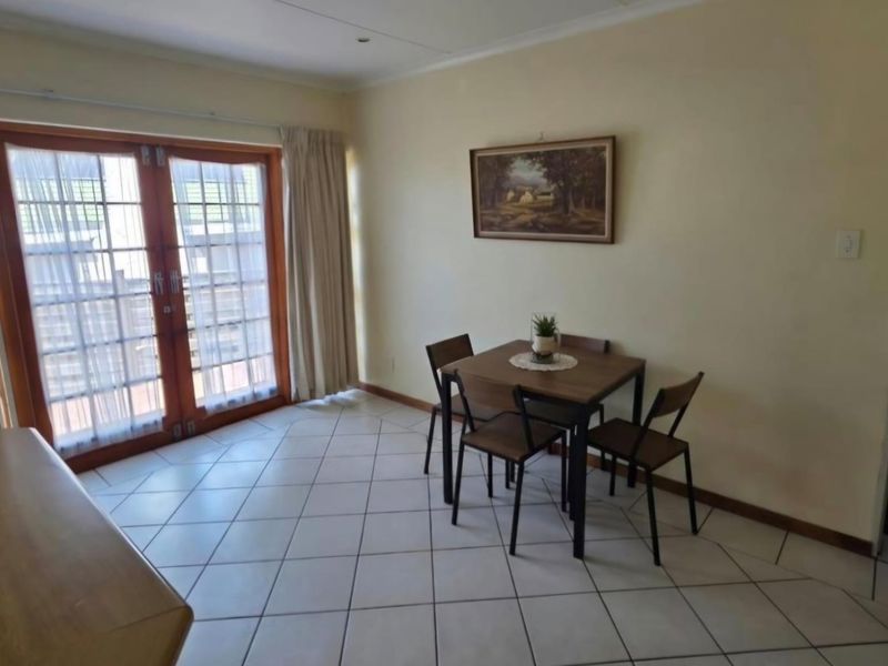 A dining area featuring tiled flooring and double glass doors providing access to the exterior.
