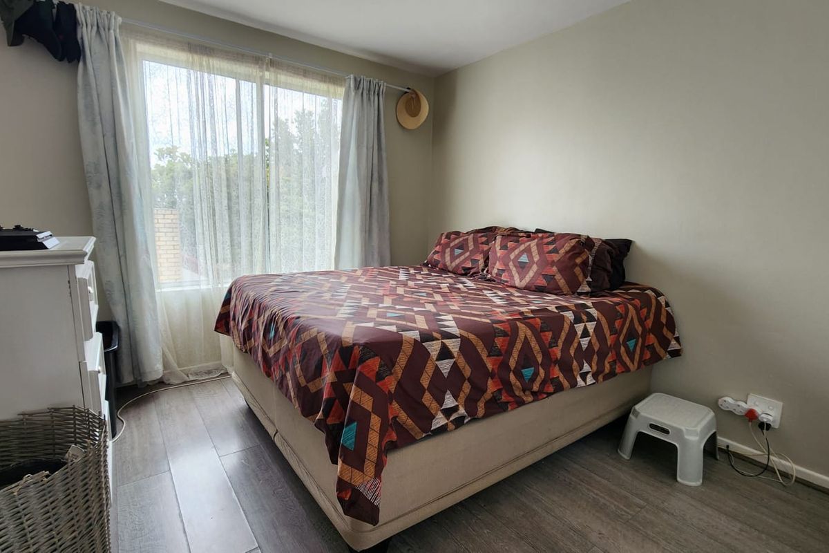 A functional bedroom featuring laminate flooring and a large sliding glass door that provides natural light.