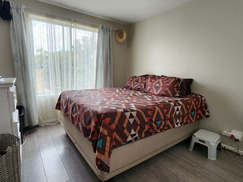 A functional bedroom featuring laminate flooring and a large sliding glass door that provides natural light.