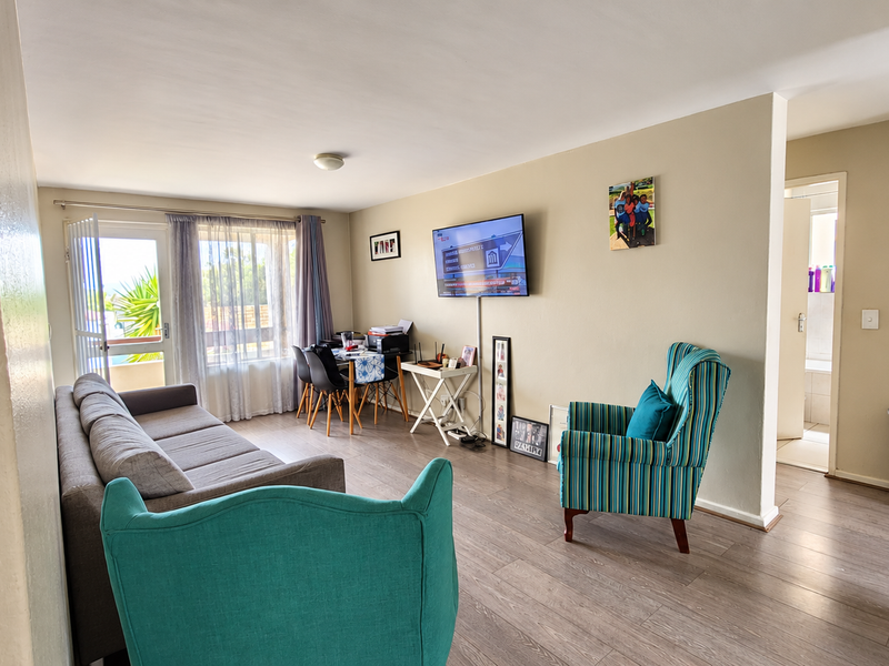 A bright open-plan living area featuring laminate flooring and a sliding glass door leading to an outdoor space.