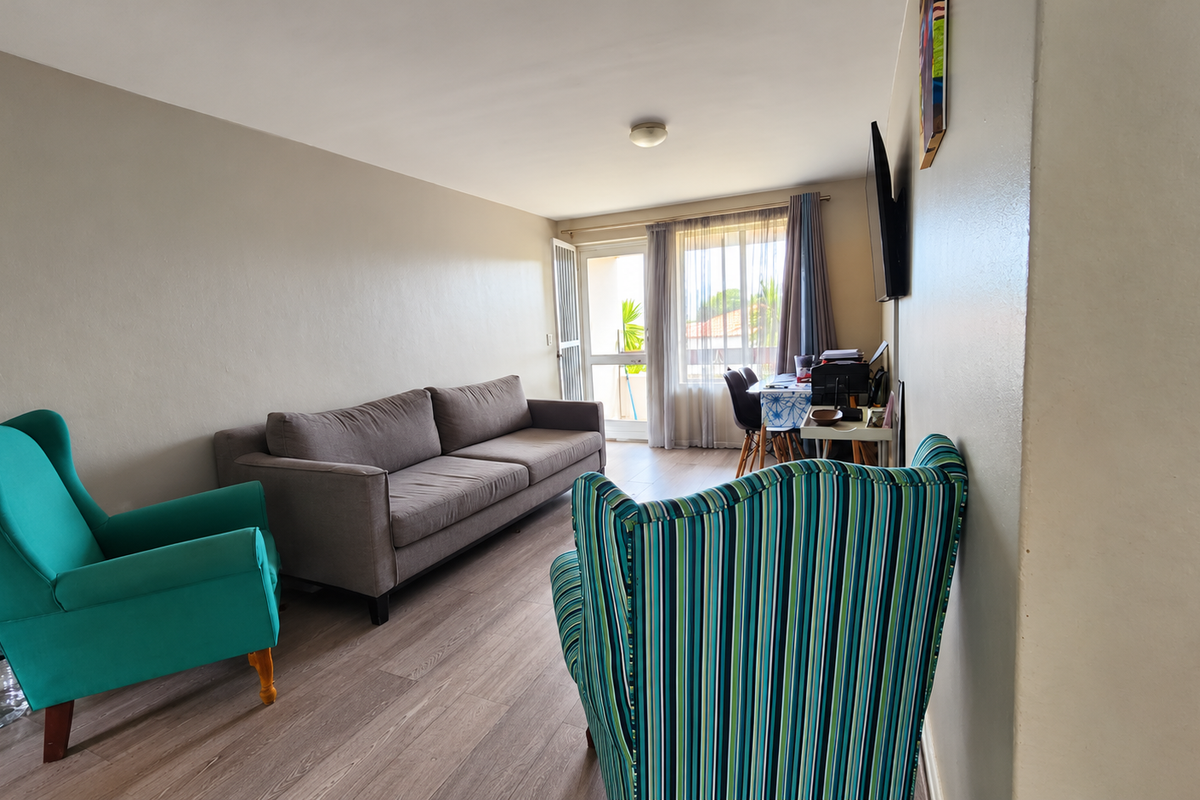 A living room featuring laminate flooring and a sliding glass door providing access to an outdoor area, with neutral wall finishes.