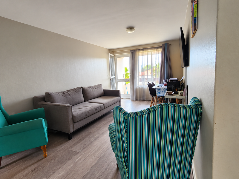 A living room featuring laminate flooring and a sliding glass door providing access to an outdoor area, with neutral wall finishes.