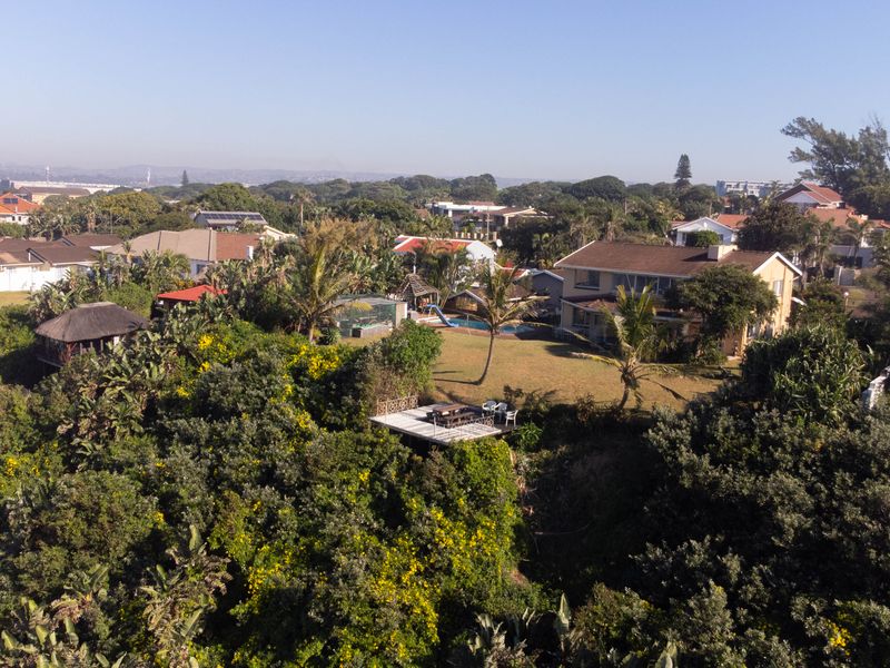 Aerial view of the property showcasing the spacious garden, swimming pool, and elevated wooden deck set within a lush, established residential neighborhood.